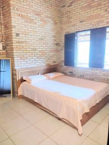 ein großes Bett in einem Zimmer mit Ziegelwand in der Unterkunft Sitio vó Dora in Aratuba