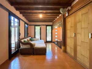 a living room with a couch and a chair and windows at Sayang Taman Villas in Sanur