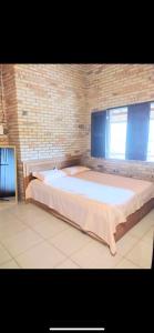 ein großes Bett in einem Zimmer mit Ziegelwand in der Unterkunft Sitio vó Dora in Aratuba