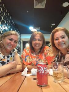 3 Frauen sitzen an einem Tisch mit einer Dose Koks in der Unterkunft Sitio vó Dora in Aratuba