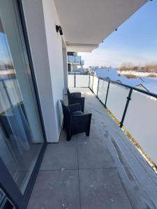 a balcony with two chairs and a view of the water at Apartamenty Słoneczne Balkony in Sarbinowo