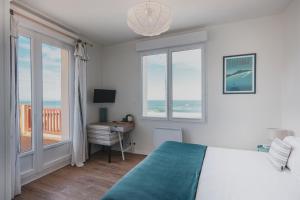 um quarto com uma cama, uma secretária e janelas em Hôtel de La Plage em Hossegor