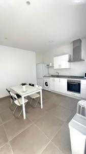 a white kitchen with a white table and chairs at Encantador Apartamento en Lebrija in Lebrija