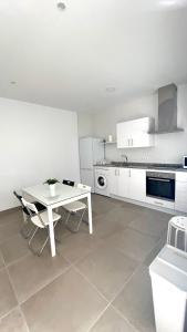 cocina blanca con mesa blanca y sillas en Encantador Apartamento en Lebrija, en Lebrija