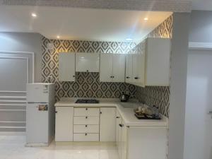 eine Küche mit weißen Schränken und einem weißen Kühlschrank in der Unterkunft جودة الحياة in Al Kharj