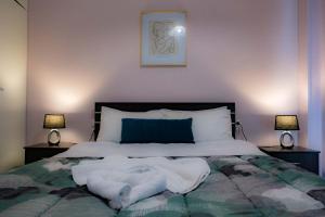 a bedroom with a bed with white sheets and two lamps at sophia's apartment in Volos