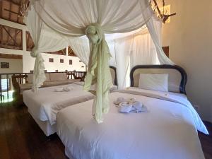 una camera con 2 letti con lenzuola bianche e un baldacchino di Sayang Taman Villas a Sanur