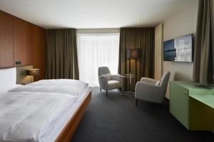 ザンクト・マルティンにあるConsulat des Weinsのベッドと椅子、窓が備わるホテルルームです。