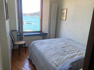 a bedroom with a window with a bed and a chair at Azzurra, sulla Calata di Portovenere in Portovenere