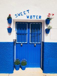 un bâtiment doté de portes bleues et de plantes en pot dans l'établissement Sweet Water Caminito del Rey, à Carratraca