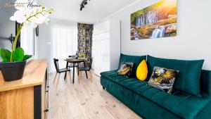 a living room with a green couch and a table at Wonder Home - Apartamenty z widokiem na góry, blisko wyciągów, szlaków turystycznych i restauracji in Karpacz
