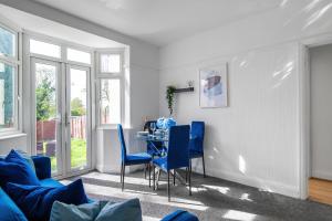 salon ze stołem i niebieskimi krzesłami w obiekcie Livestay 3 Bed House in Hendon Private Garden&Parking w mieście Colindale