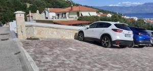 two cars are parked next to a wall at Old Town Lux in Baška