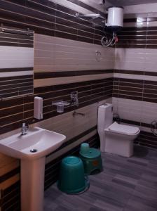 a bathroom with a sink and a toilet at Advent Hotel in Sūrajpur