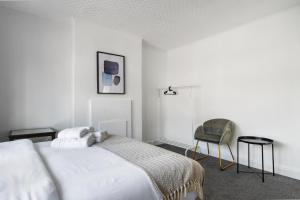 biała sypialnia z łóżkiem i krzesłem w obiekcie Livestay 3 Bed House in Hendon Private Garden&Parking w mieście Colindale