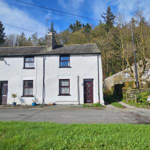une maison blanche avec une porte rouge dans une rue dans l'établissement Bobtail Cottage by Woodland Park, à Staveley