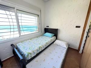 uma pequena cama em um quarto com janela em Belyounech vue sur mer et montagne 2 bederoom em Tetouan