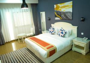 a bedroom with a large white bed with blue walls at Saḟeer international alkhuwair in Muscat