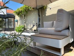 a couch sitting under an umbrella on a patio at B&B Grain de Sable in Knokke-Heist