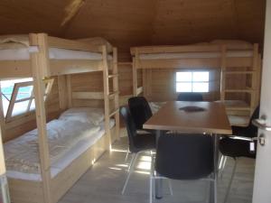 Cette chambre comprend des lits superposés, une table et des chaises. dans l'établissement Maritime Freizeit Camp "MFC" Erfurter Seen, à Stotternheim