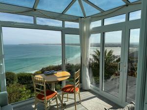 a screened in porch with a table and chairs and the ocean at Huers Hide in Carbis Bay