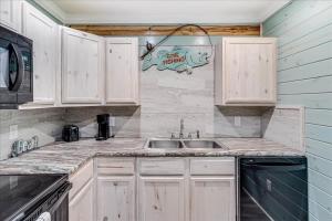 a kitchen with white cabinets and a sink at Blue Marlin Cottage (Anchor Courts #3) in Port Aransas