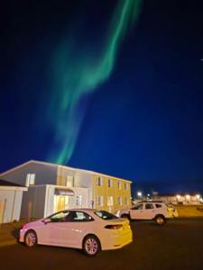 two cars parked in a parking lot under the northern lights at Hotel Kanslarinn Hella in Hella