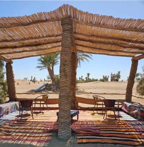 a pavilion with chairs and tables on the beach at Desert Waves Excursion in Mhamid