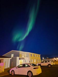 two cars parked in front of a building under the aurora at Hotel Kanslarinn Hella in Hella
