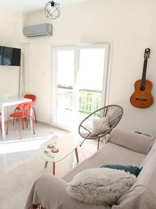 ein Wohnzimmer mit einem Sofa, einem Tisch und einer Gitarre in der Unterkunft Ilion apartments in Athen