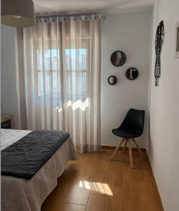 ein Schlafzimmer mit einem Bett, einem Stuhl und einem Fenster in der Unterkunft APARTAMENTO APARTACLUB REFORMADO in Chiclana de la Frontera