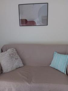 eine Couch mit zwei Kissen und ein Bild an der Wand in der Unterkunft Ilion apartments in Athen