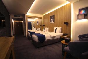 Monarch Hotel Amman في عمّان: غرفه فندقيه اربع اسره وتلفزيون