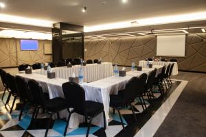 ein Konferenzraum mit Tischen, Stühlen und einer Leinwand in der Unterkunft Monarch Hotel Amman in Amman
