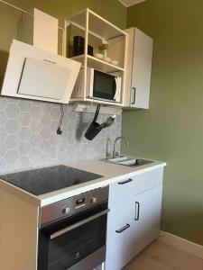 uma cozinha com armários brancos, um lavatório e um fogão em G23 em Sarpsborg