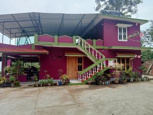 ein rosa Haus mit einer Treppe davor in der Unterkunft soms estate stay in Madikeri