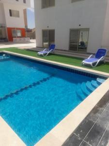 a swimming pool with two blue chairs next to a building at Alfayrouz house in Hurghada