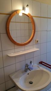 ein Bad mit einem Waschbecken und einem Wandspiegel in der Unterkunft Ferienhäuser Freiblick in Ditzumerverlaat