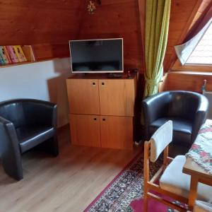 sala de estar con 2 sillas y TV de pantalla plana en Belvárosi Apartman Kőszeg, en Kőszeg