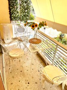 une table en verre avec des chaises et un vase de fleurs sur le balcon dans l'établissement DP Riviera Apartment, à Athènes