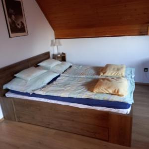 - un lit avec une tête de lit en bois et des oreillers dans l'établissement Belvárosi Apartman Kőszeg, à Kőszeg