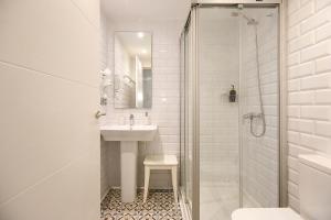 y baño blanco con lavabo y ducha. en Pensión Balerdi Autocheck-in, en San Sebastián