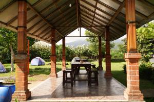 a wooden pavilion with a table and tents at Bali Strawberry Glamping and Camp Bedugul in Tabanan