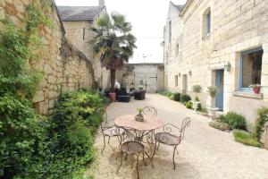 a patio with a table and chairs in a courtyard at Jallanges in Fontevraud-l'Abbaye