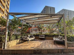 a pergola with two couches on a wooden deck at Ambition studio apartment at weekend address in Bhatha