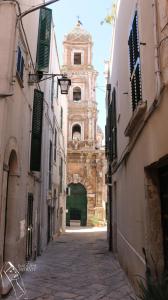 an alley with a building with a clock tower at Le Badesse Mitrate by il pumo di puglia in Conversano