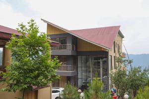 a building with a red roof and a tree at Vista Valle in Murree