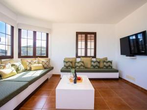 ein Wohnzimmer mit grünen Sofas und einem TV in der Unterkunft Villa Palmera La Vegueta Villas in Tinajo