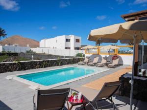 einen Pool mit Stühlen und einem Sonnenschirm in der Unterkunft Villa Verol La Vegueta Villas in Tinajo