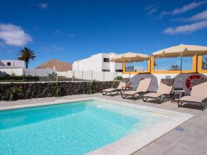 einen Pool mit zwei Stühlen und Sonnenschirmen neben in der Unterkunft Villa Verol La Vegueta Villas in Tinajo